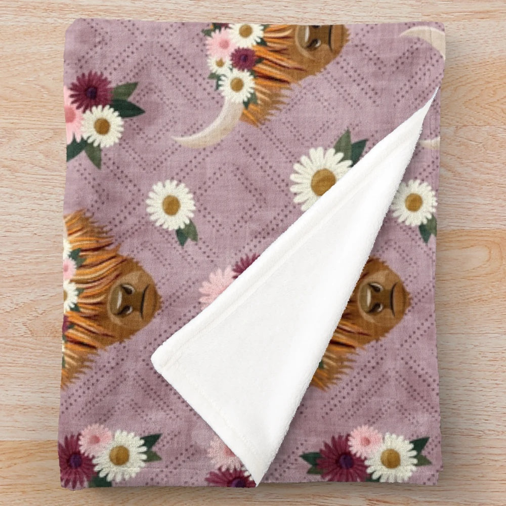 Floral crowned highland cows printed on a mauve plush blanket