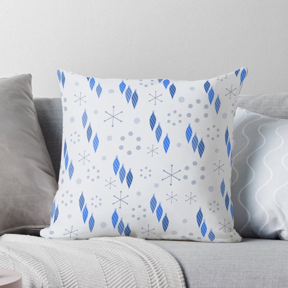 A mid century modern style pillow featuring a winter holiday design with sputnik starbursts, snowflakes, and ornaments.