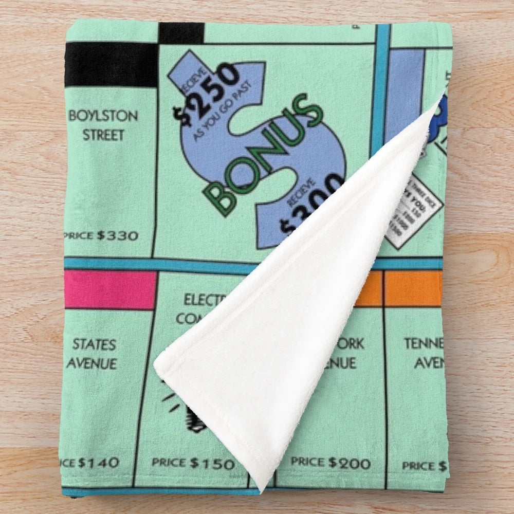 Soft and cozy plush blanket with a Monopoly-inspired board game design