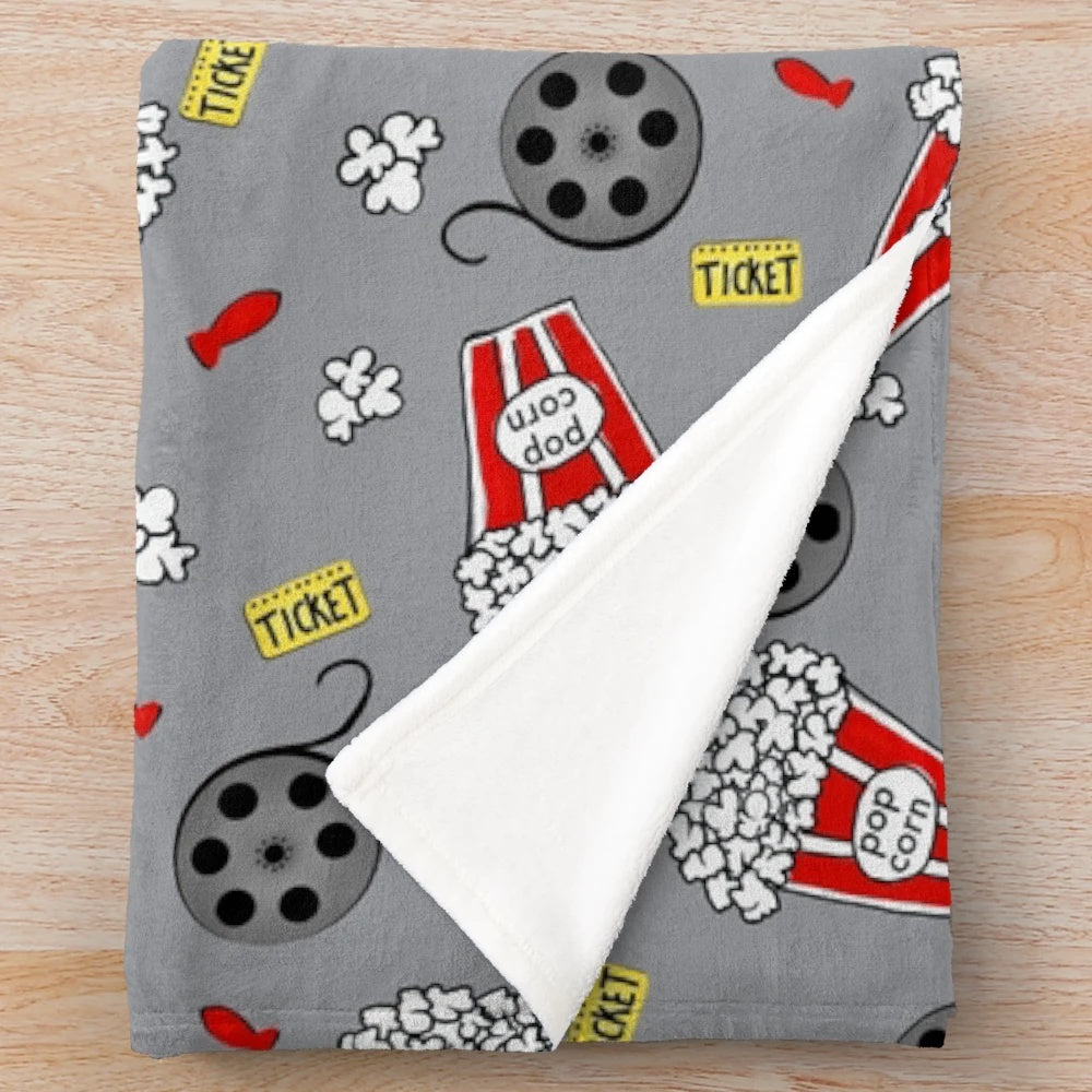 A cozy plush blanket featuring a movie night and snack themed design