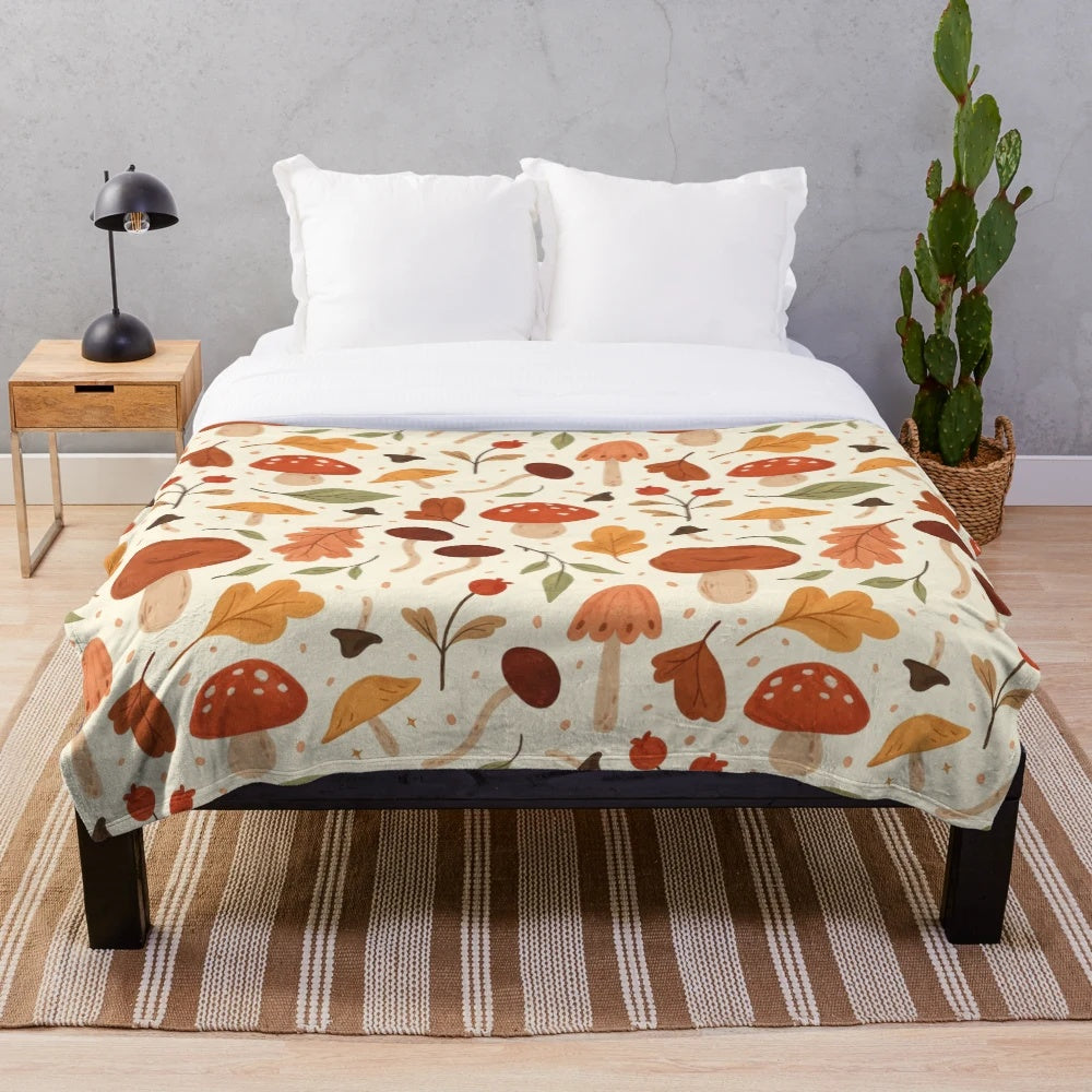 Soft plush blanket featuring a botanical pattern of mushrooms and fall leaves