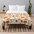 Soft plush blanket featuring a botanical pattern of mushrooms and fall leaves