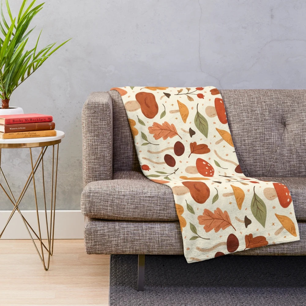 Soft plush blanket featuring a botanical pattern of mushrooms and fall leaves