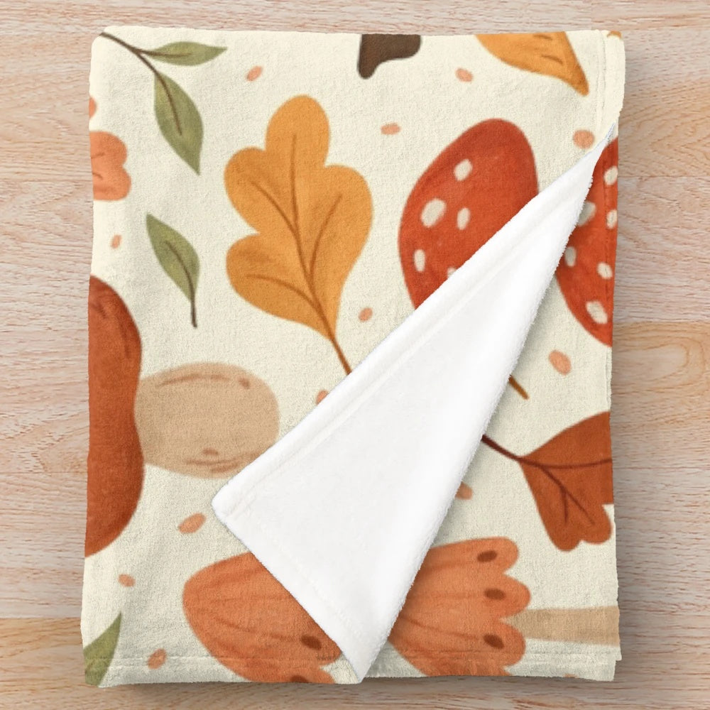 Soft plush blanket featuring a botanical pattern of mushrooms and fall leaves