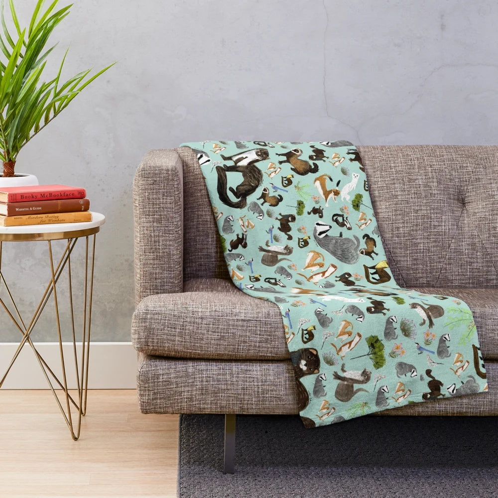 Plush blanket featuring a whimsical pattern of mustelid species like badgers, otters, and martens
