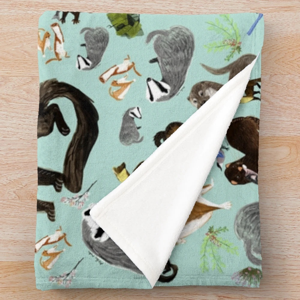 Plush blanket featuring a whimsical pattern of mustelid species like badgers, otters, and martens