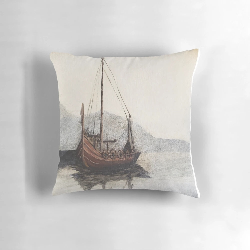 A cozy decorative pillow featuring a moody, foggy seascape painting of a lone viking ship on the water, surrounded by mountains.