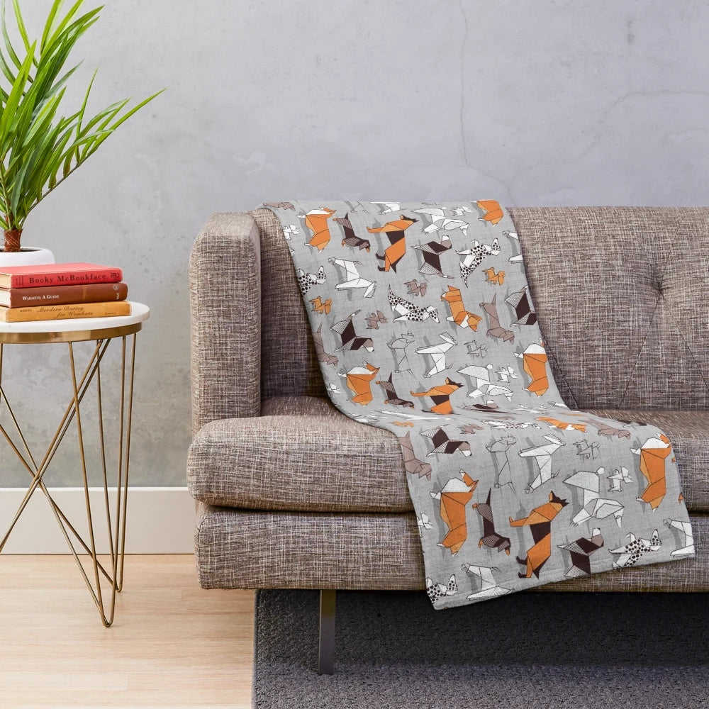 Soft plush blanket featuring an origami-style dog illustration on a grey linen textured background