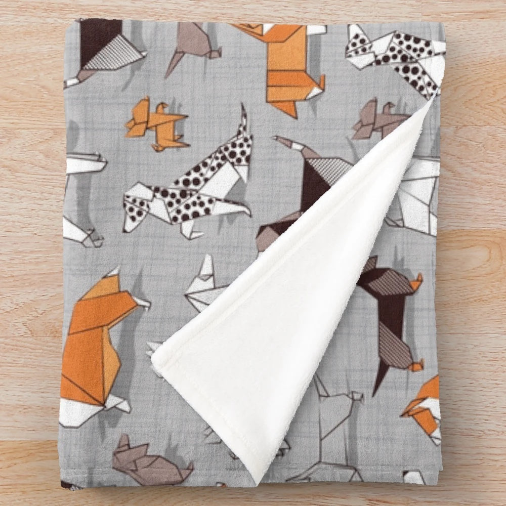 Soft plush blanket featuring an origami-style dog illustration on a grey linen textured background