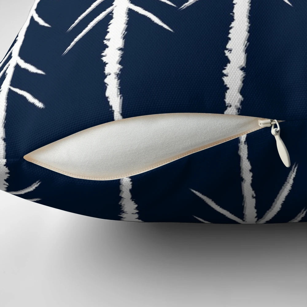 A navy blue and grey pillow with a sketch-style pine tree design and white arrows