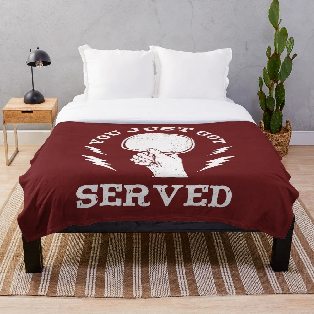 A plush blanket featuring a hand holding a ping pong paddle