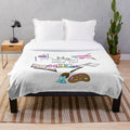 Plush blanket with a pastel rainbow design and illustrations of hobbies and crafts