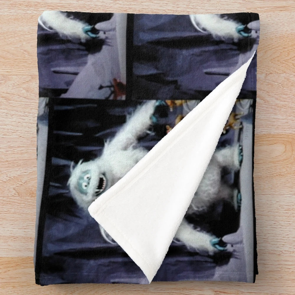 Cozy plush blanket with Christmas movie characters like Rudolph, Bumble, and Yukon Cornelius