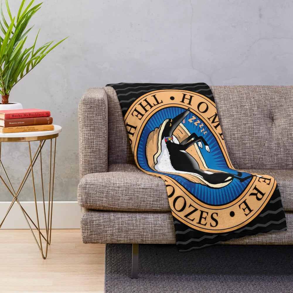 Greyhound, whippet, or lurcher dog sleeping on a soft, plush blanket with a cartoon design