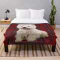 West Highland White Terrier sitting on a scotch plaid plush blanket