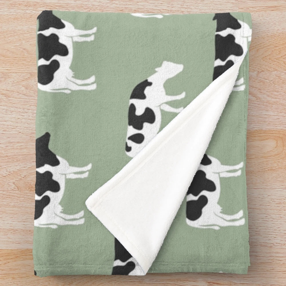 Plush blanket featuring dairy cows against a sage green background