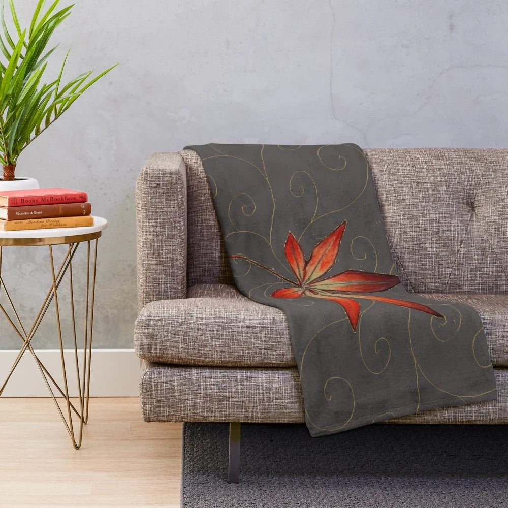 Plush blanket featuring a maple leaf design with gold filigree on a gray background