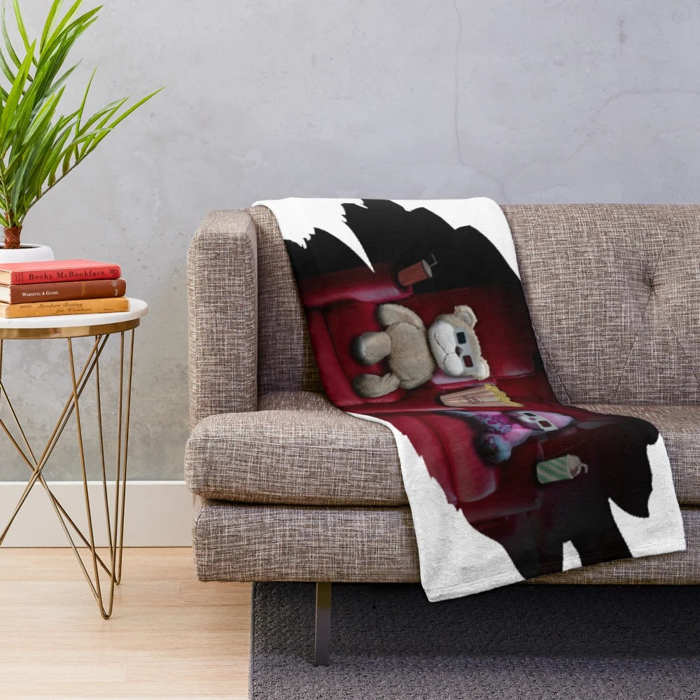 Plush blanket with teddy bears watching a movie in a cinema setting