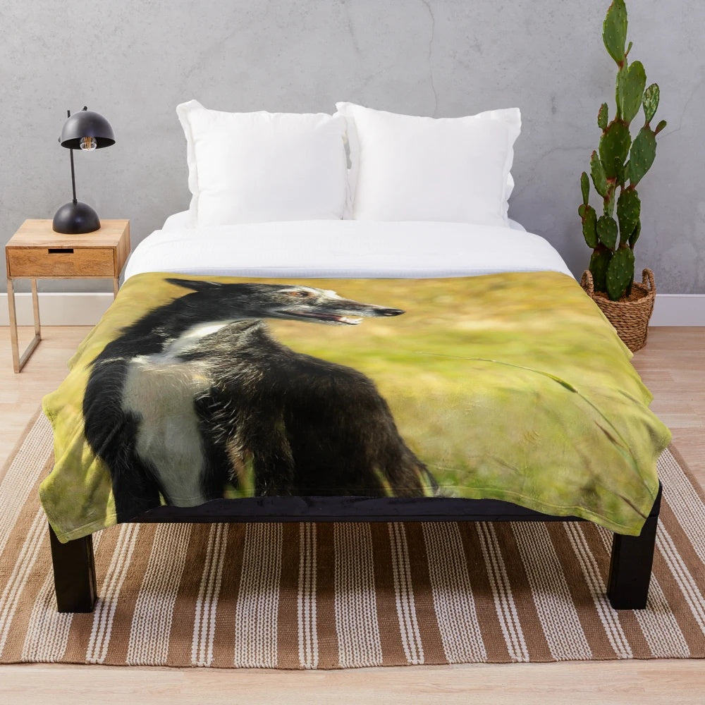 Resting lurcher dog on plush blanket with autumnal countryside background