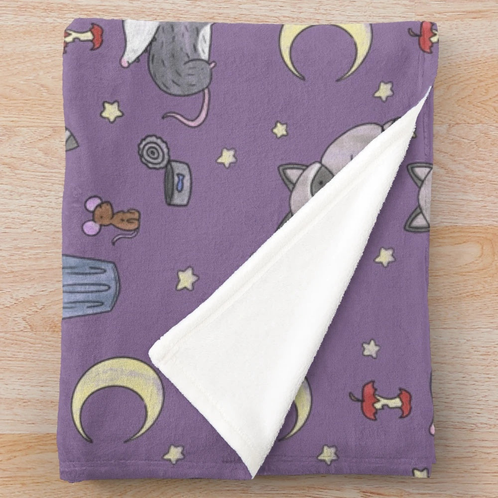 Plush blanket featuring a pattern of raccoons, opossums, and other nocturnal critters in a trash-themed design