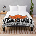 Plush blanket with illustration of vibrant orange maple leaves in an autumn landscape