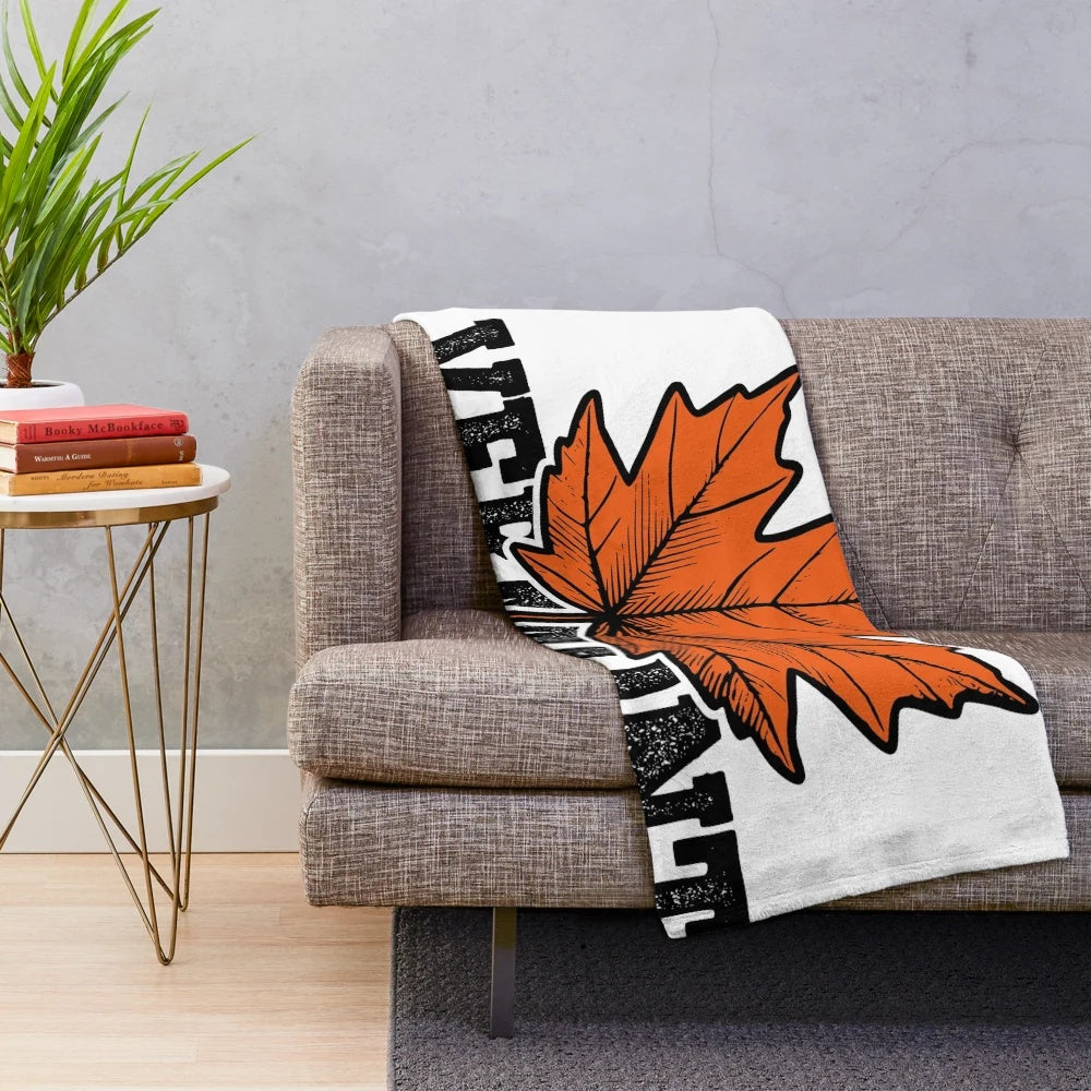 Plush blanket with illustration of vibrant orange maple leaves in an autumn landscape