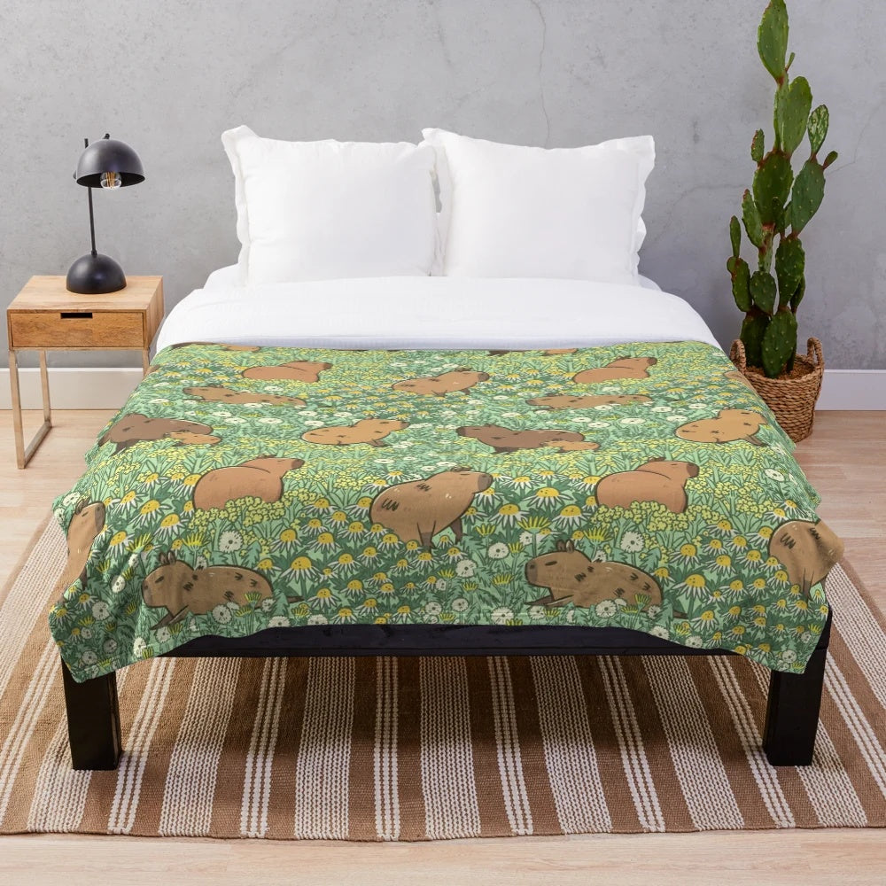Plush blanket featuring a repeating pattern of capybaras in a lush green and yellow meadow