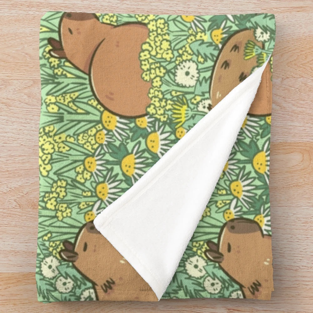 Plush blanket featuring a repeating pattern of capybaras in a lush green and yellow meadow