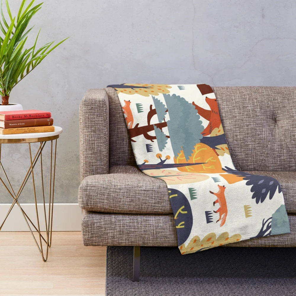 Plush blanket featuring a forest animal design with bears, foxes, and autumn colors