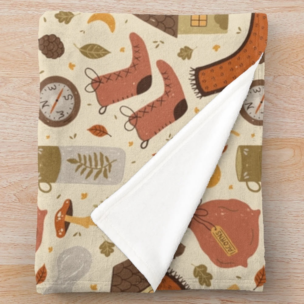 Plush blanket with nature-inspired pattern featuring woods, leaves, and acorns