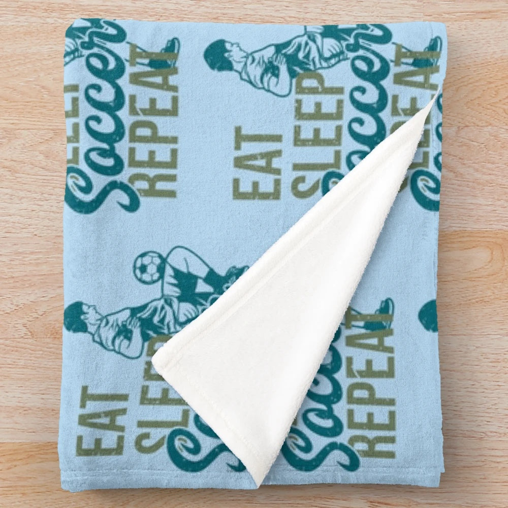 Plush soccer-themed blanket with "Eat Sleep Soccer Repeat" design