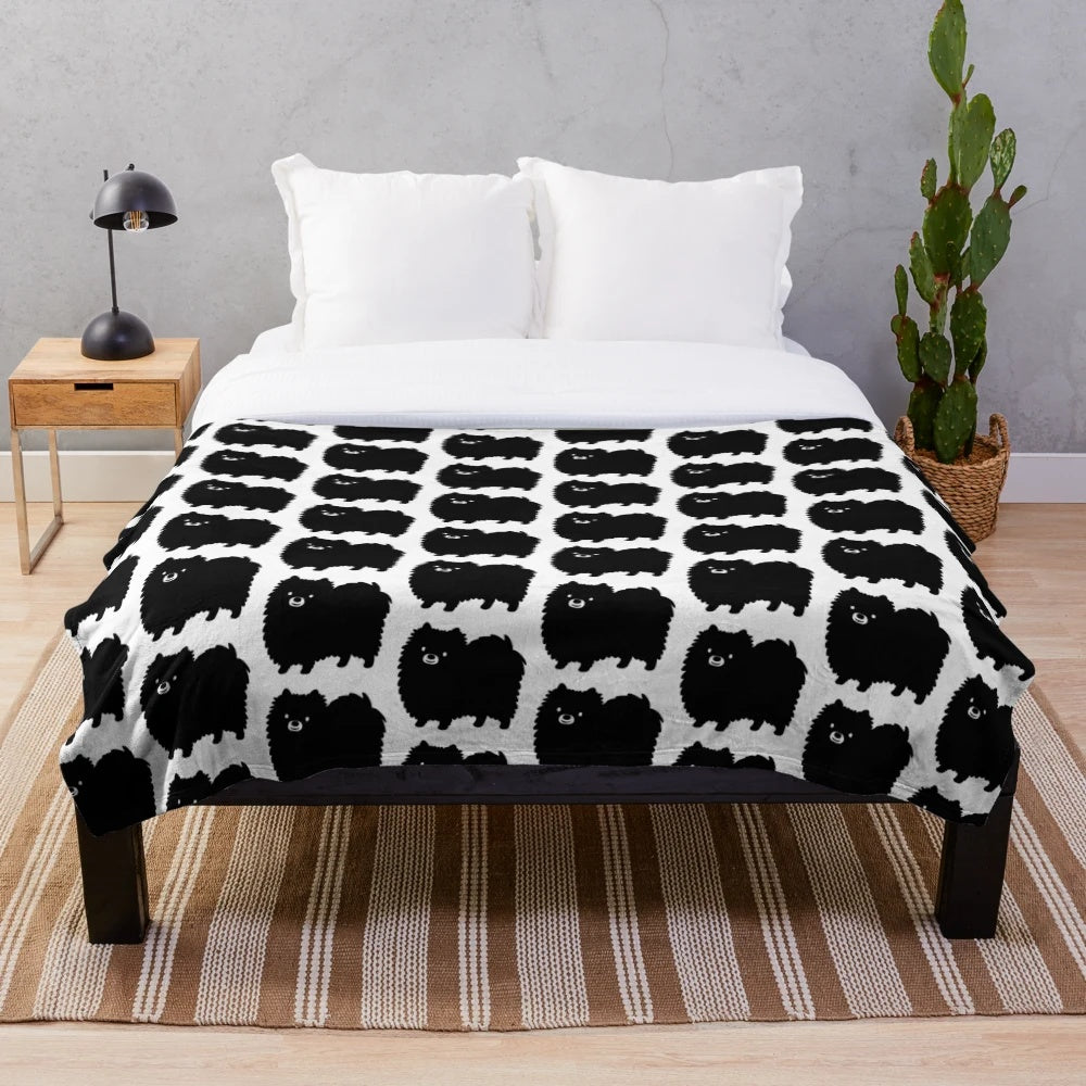 Fluffy black pomeranian dog on a soft plush blanket