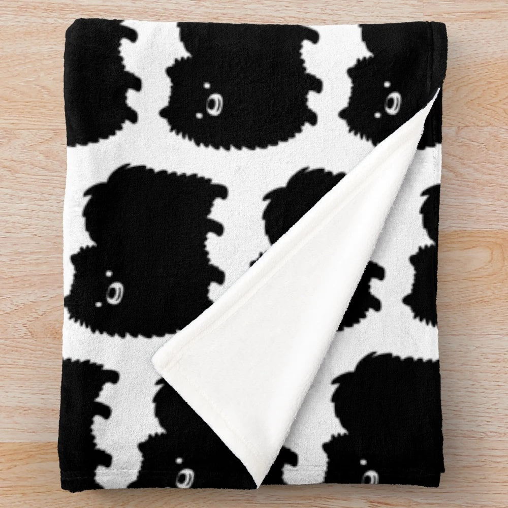 Fluffy black pomeranian dog on a soft plush blanket