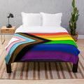 A soft and inviting plush blanket featuring the Progress Pride flag design
