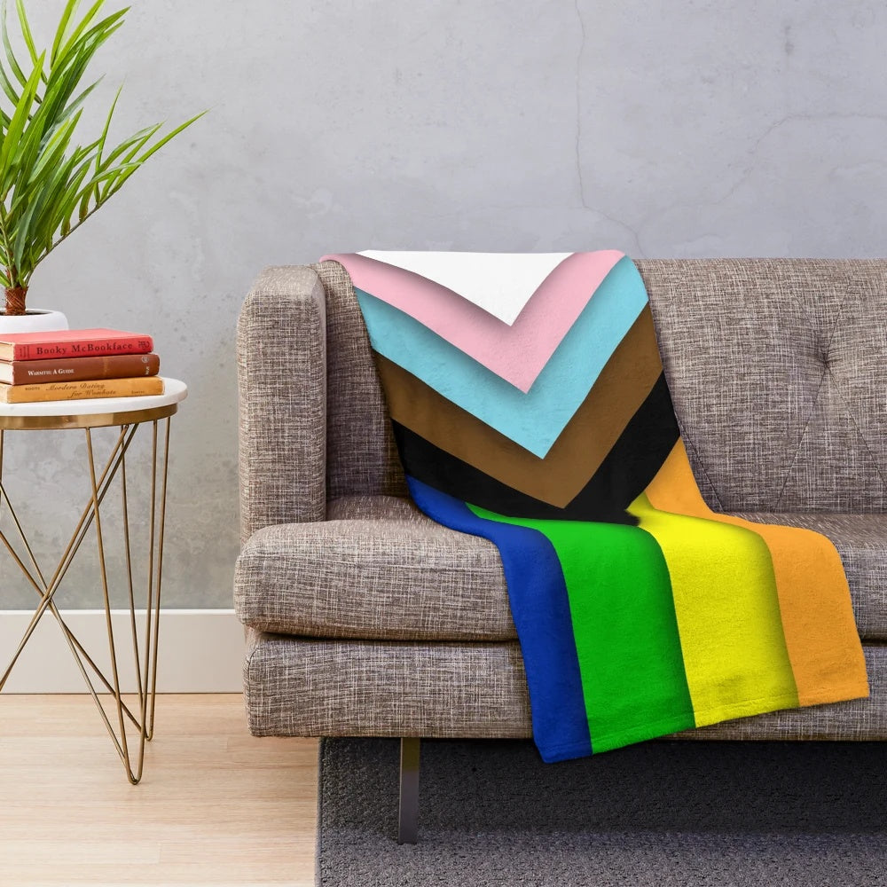 A soft and inviting plush blanket featuring the Progress Pride flag design