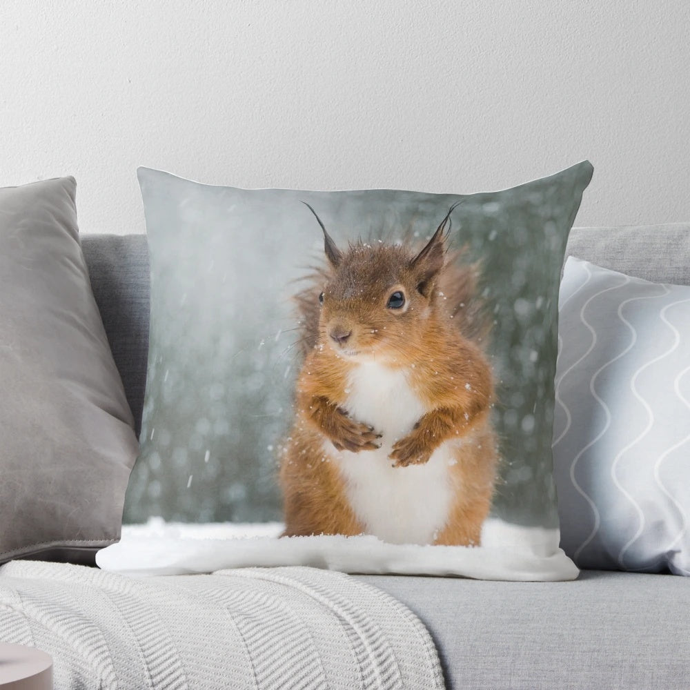 A soft, plush throw pillow featuring a charming red squirrel surrounded by a winter snowscape.