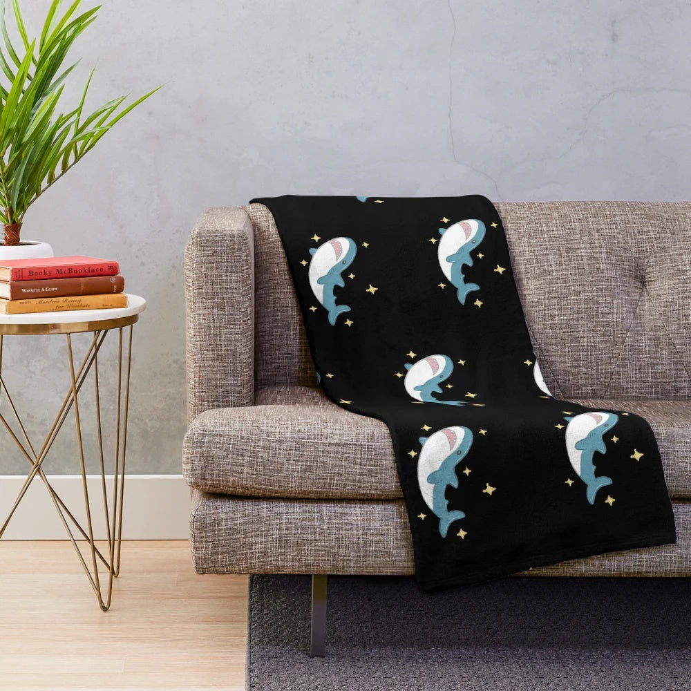 Blahaj the shark plush blanket against a black background