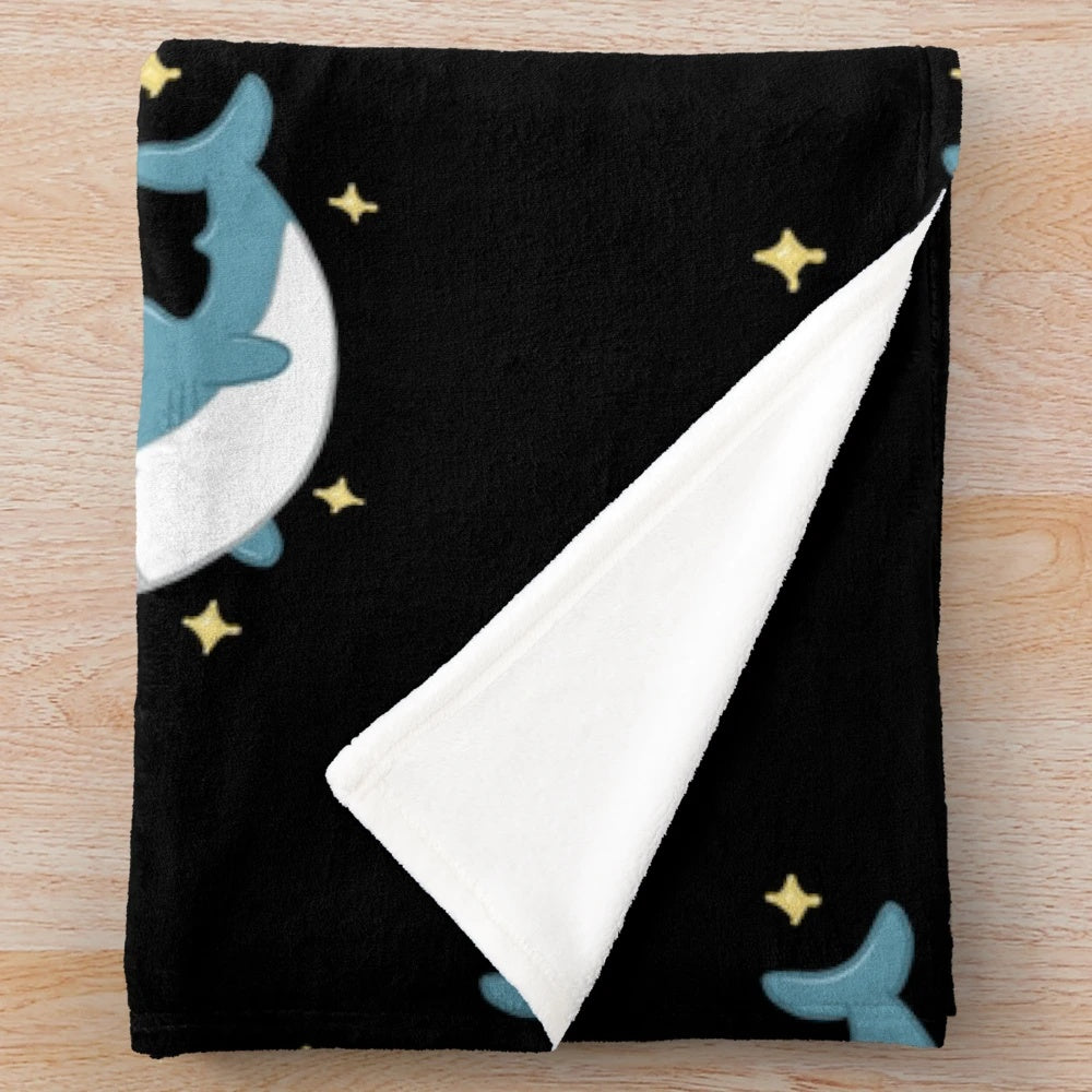 Blahaj the shark plush blanket against a black background
