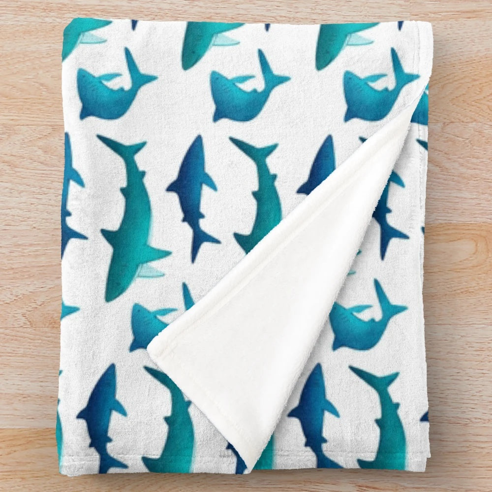 Plush blanket featuring a collection of shark designs in teal and blue colors