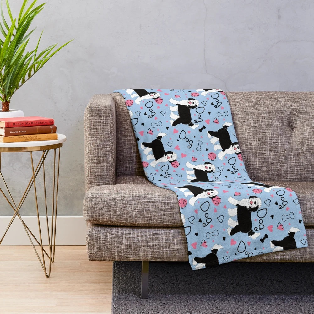 Cute black and white sheepadoodle puppy on a soft, plush blanket