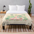 A soft, plush blanket featuring a green and pink shibakura plant design and a shiba dog