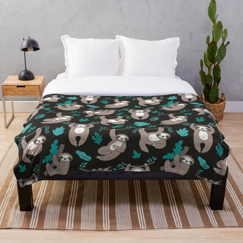 Soft and plush sloth blanket with sloths hanging on a black background