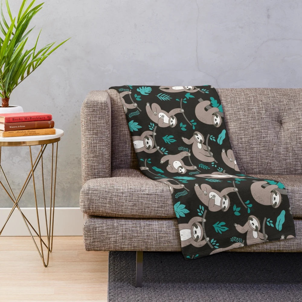 Soft and plush sloth blanket with sloths hanging on a black background