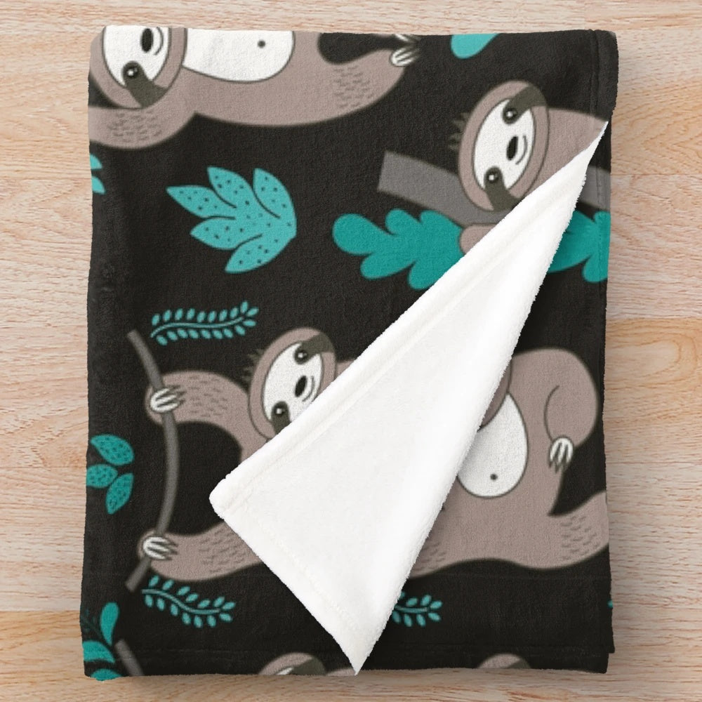 Soft and plush sloth blanket with sloths hanging on a black background