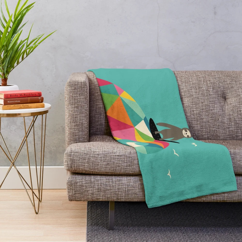 Colorful geometric patterned plush blanket with a surfing sloth design