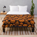 Plush blanket featuring smiling pumpkins on a starry night background