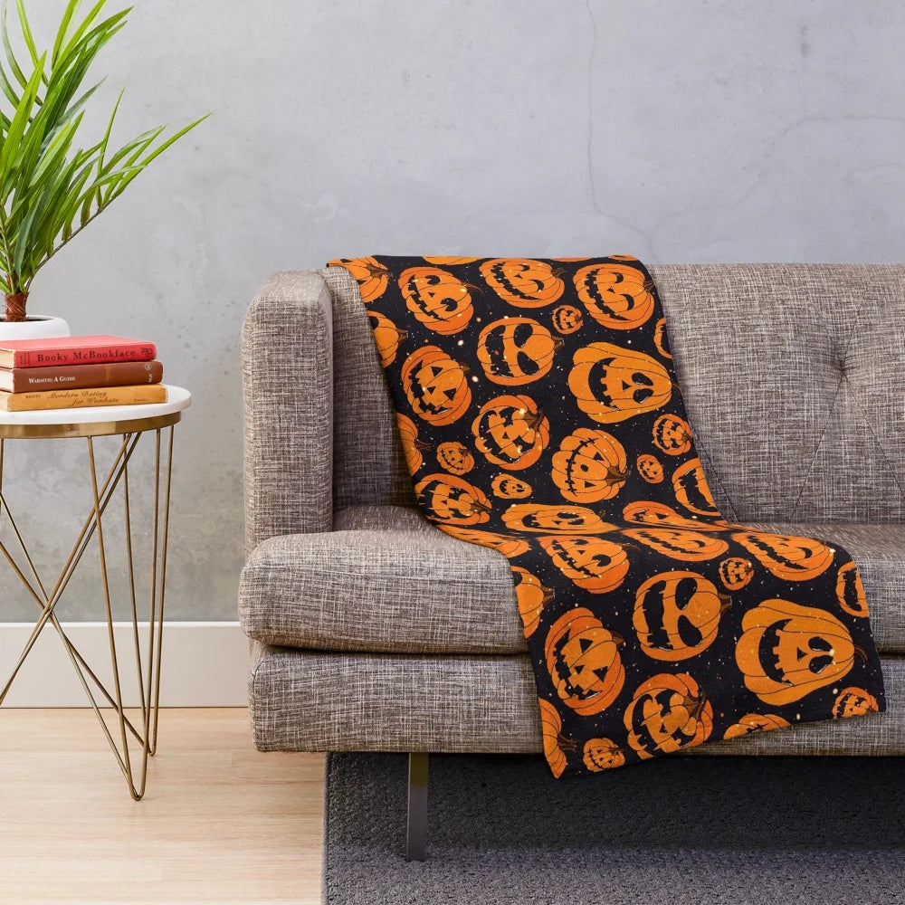 Plush blanket featuring smiling pumpkins on a starry night background