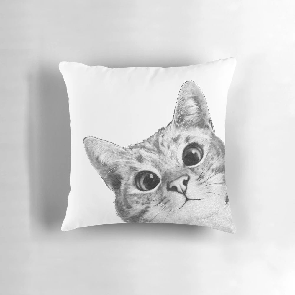 A black and white cat peeking out from a plush, comfortable pillow