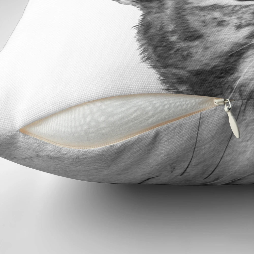 A black and white cat peeking out from a plush, comfortable pillow