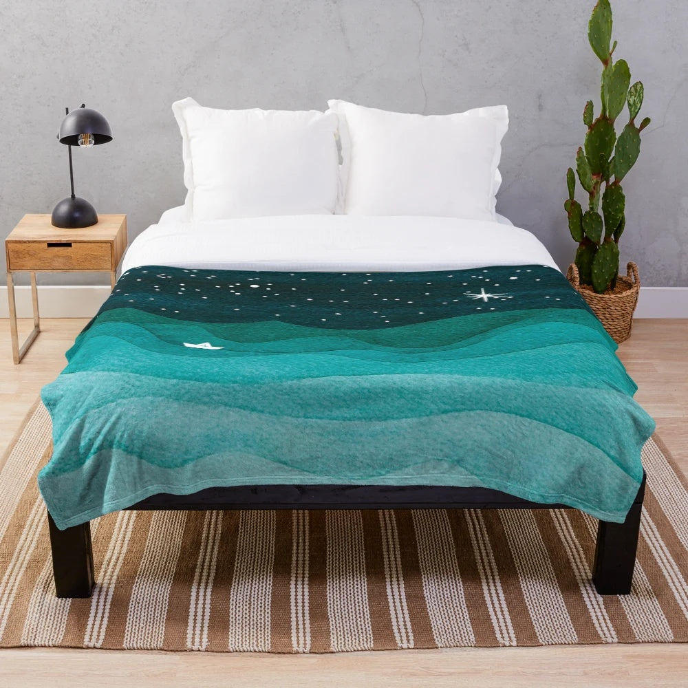 Plush blanket with a starry ocean watercolor design featuring a teal sailboat